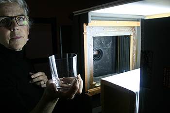Amanda Means working with the water glass and her wooden enlarger in the darkroom. Courtesy of the artist.